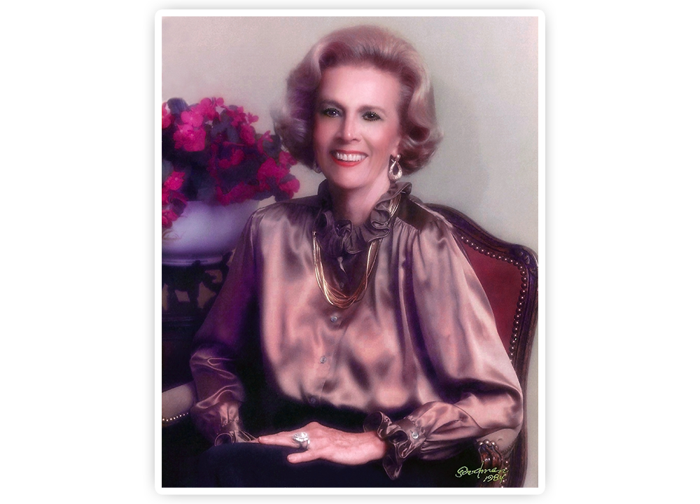 A portrait of Jane Chilton Justin posing for the camera smiling, wearing a brown silk shirt.